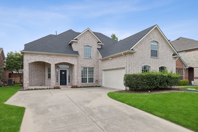 view of front of house with cooling unit, a garage, and a front lawn