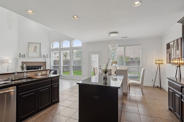 kitchen with a notable chandelier, stainless steel dishwasher, light tile patterned flooring, sink, and a kitchen island