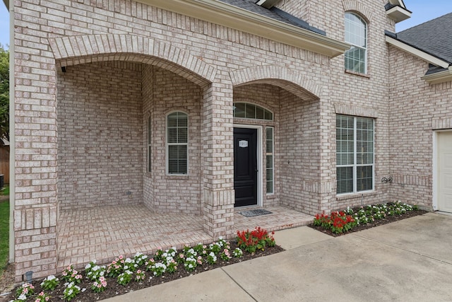 property entrance featuring brick siding and a shingled roof