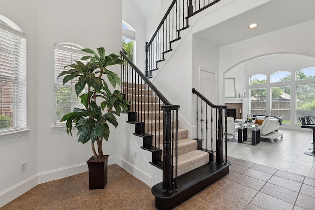 staircase featuring tile patterned floors, plenty of natural light, and a towering ceiling