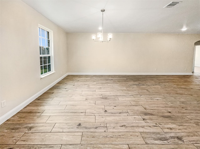 empty room with a notable chandelier and hardwood / wood-style flooring