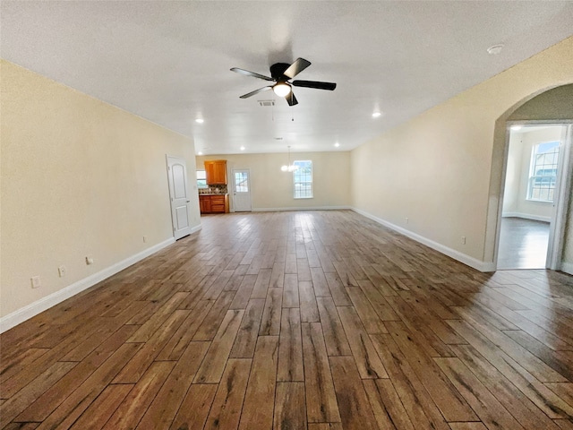 unfurnished living room featuring dark hardwood / wood-style flooring, ceiling fan, and a textured ceiling