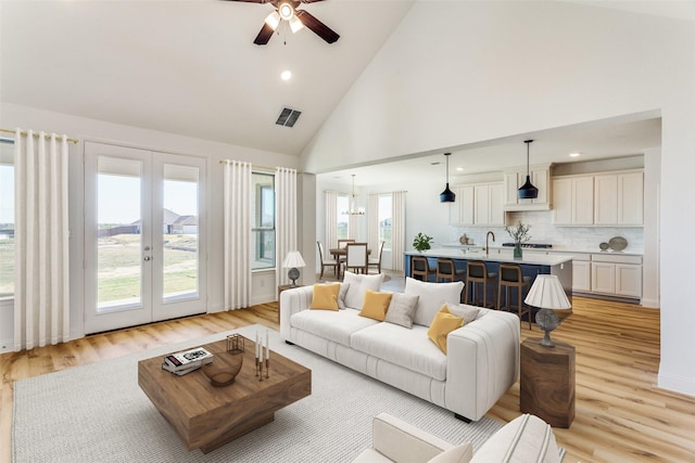 living room with ceiling fan, high vaulted ceiling, french doors, light wood-style flooring, and visible vents