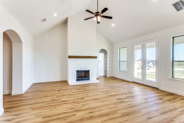 unfurnished living room featuring high vaulted ceiling, light wood-style flooring, a brick fireplace, and visible vents