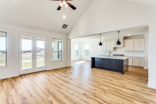 kitchen with a center island with sink, open floor plan, hanging light fixtures, light countertops, and white cabinetry