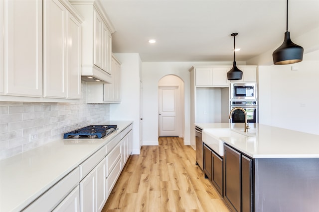 kitchen featuring appliances with stainless steel finishes, light countertops, a sink, and decorative light fixtures