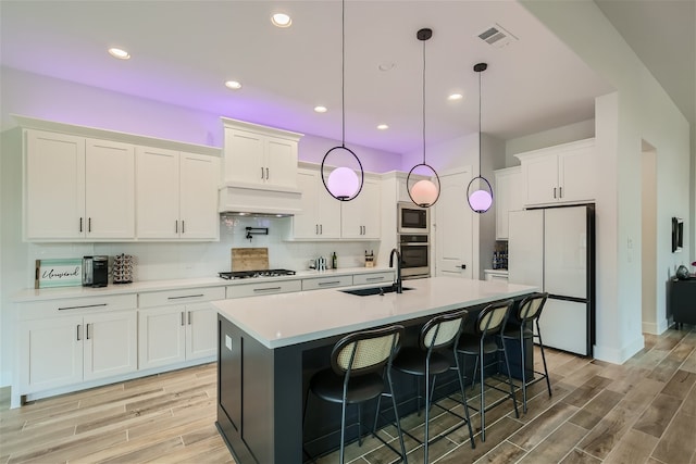 kitchen with tasteful backsplash, an island with sink, sink, a breakfast bar area, and appliances with stainless steel finishes