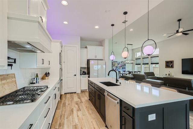 kitchen featuring stainless steel appliances, hanging light fixtures, tasteful backsplash, a kitchen island with sink, and sink