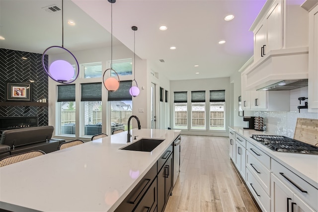 kitchen with a healthy amount of sunlight, white cabinets, backsplash, and pendant lighting