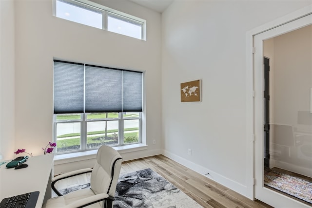 office featuring a towering ceiling and light hardwood / wood-style flooring