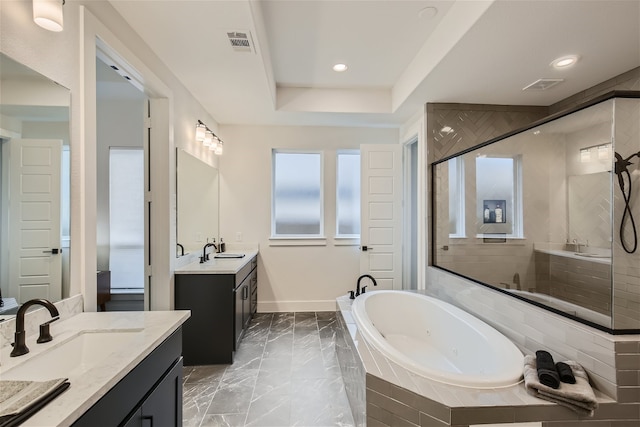 bathroom with tiled bath, dual vanity, a tray ceiling, and tile flooring