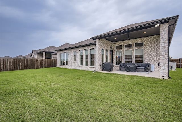 back of property with a patio, an outdoor living space, and a lawn