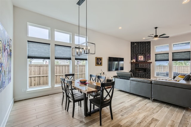 dining room with plenty of natural light, ceiling fan with notable chandelier, light hardwood / wood-style floors, and a fireplace