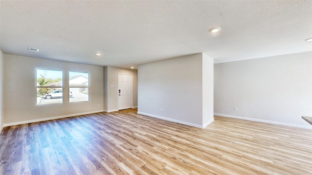 empty room with a textured ceiling and light wood-type flooring