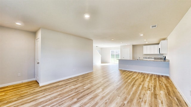 unfurnished living room featuring light hardwood / wood-style flooring and sink