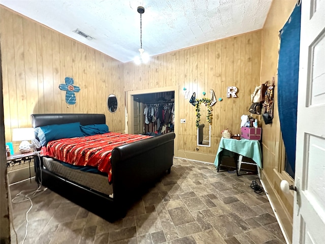 bedroom featuring a walk in closet and wooden walls