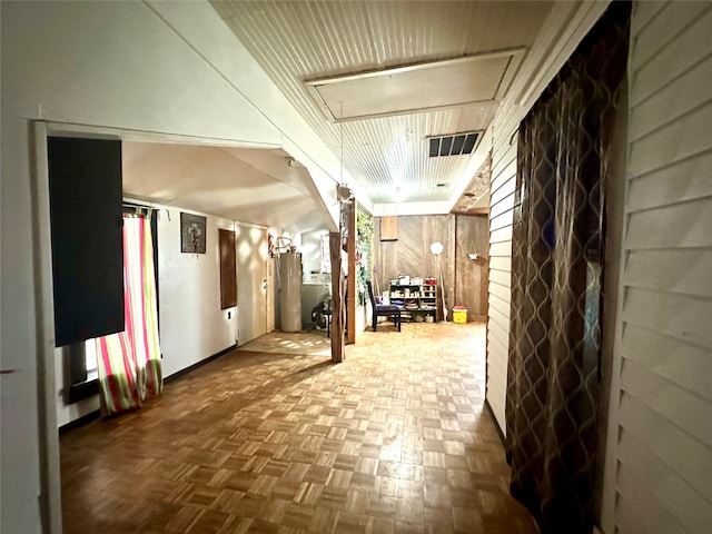 corridor featuring wooden walls, water heater, and parquet flooring