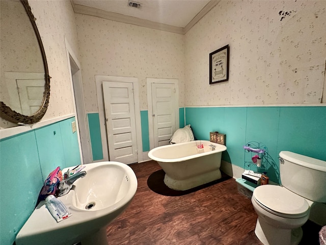 bathroom featuring sink, crown molding, hardwood / wood-style flooring, toilet, and a tub