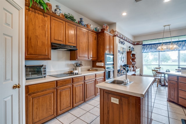 kitchen featuring an island with sink, appliances with stainless steel finishes, sink, light tile floors, and pendant lighting