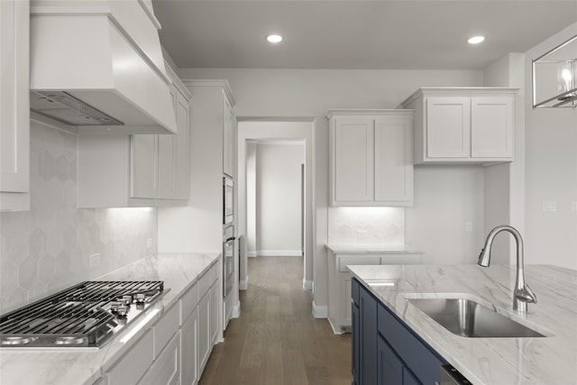 kitchen with sink, custom exhaust hood, light stone countertops, dark hardwood / wood-style floors, and stainless steel appliances