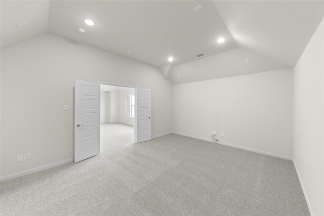 unfurnished bedroom featuring light carpet and vaulted ceiling