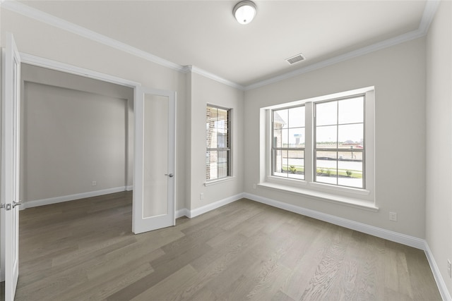 empty room featuring hardwood / wood-style floors, ornamental molding, and a healthy amount of sunlight