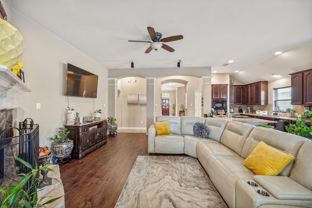 living room featuring ceiling fan, decorative columns, vaulted ceiling, dark hardwood / wood-style flooring, and sink