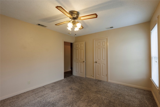 carpeted empty room with a ceiling fan, visible vents, a textured ceiling, and baseboards