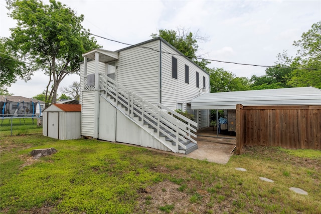 view of side of property featuring a shed, a trampoline, and a yard