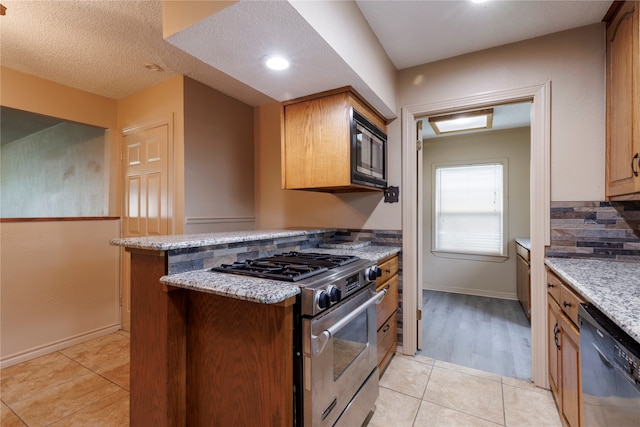 kitchen with light wood-type flooring, light stone counters, built in microwave, dishwashing machine, and high end range