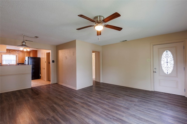 unfurnished living room with visible vents, ceiling fan, a textured ceiling, wood finished floors, and baseboards