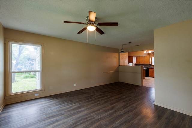 unfurnished living room with a healthy amount of sunlight, dark hardwood / wood-style flooring, ceiling fan, and a textured ceiling