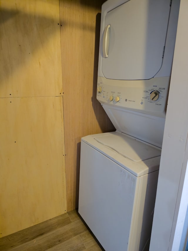 laundry area featuring stacked washer / dryer and light hardwood / wood-style floors