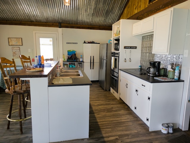 kitchen featuring white cabinetry, a barn door, black appliances, dark wood-type flooring, and sink