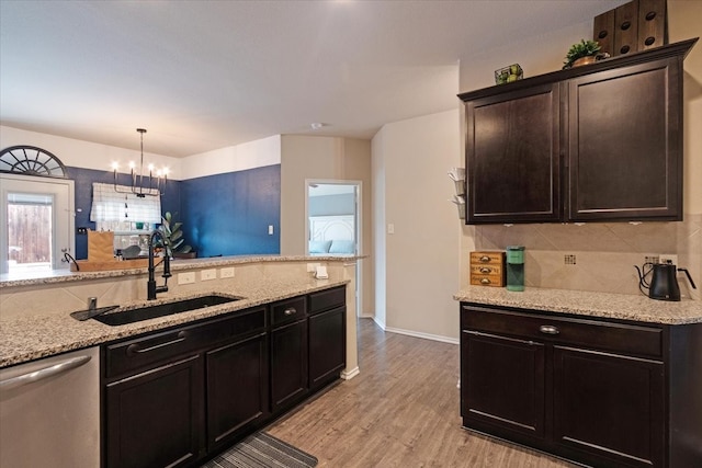 kitchen featuring decorative light fixtures, dishwasher, sink, backsplash, and light hardwood / wood-style floors