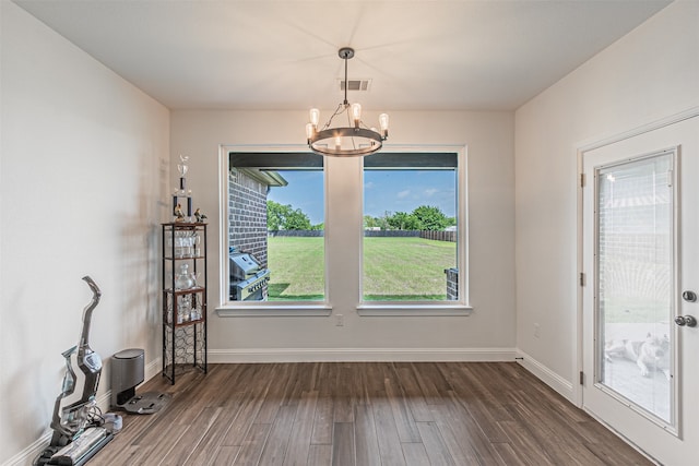 unfurnished dining area featuring a notable chandelier, a wealth of natural light, and dark wood-type flooring