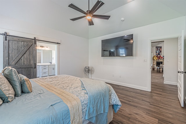 bedroom with dark hardwood / wood-style floors, ceiling fan, vaulted ceiling, ensuite bath, and a barn door