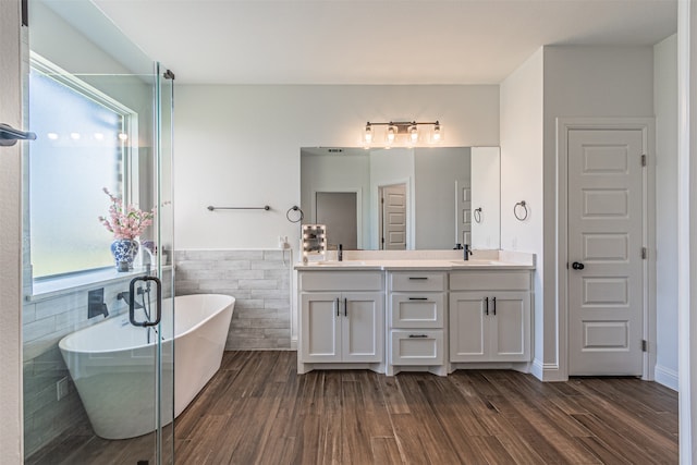 bathroom featuring dual bowl vanity, tile walls, hardwood / wood-style flooring, and a bathing tub