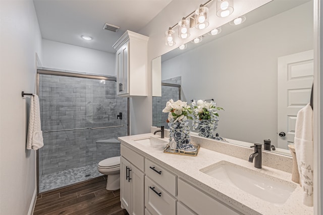 bathroom featuring double sink vanity, toilet, and a shower with door