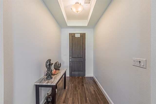 doorway to outside featuring a raised ceiling and dark hardwood / wood-style flooring