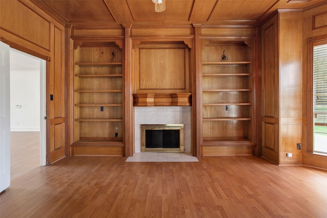 unfurnished living room featuring built in shelves, light hardwood / wood-style floors, wood ceiling, and a fireplace