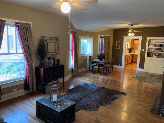 living room featuring wood-type flooring, ceiling fan, and vaulted ceiling