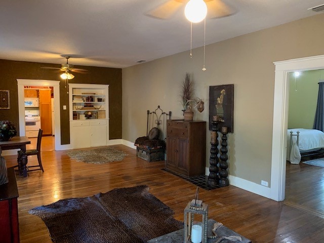 living room with dark hardwood / wood-style floors, built in features, and ceiling fan