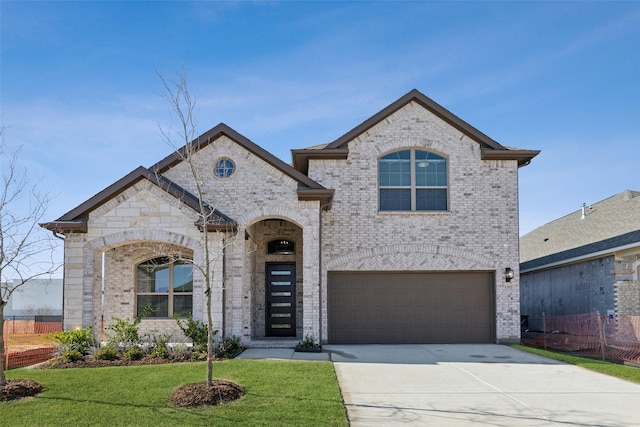 french country inspired facade featuring brick siding, concrete driveway, fence, a garage, and a front lawn