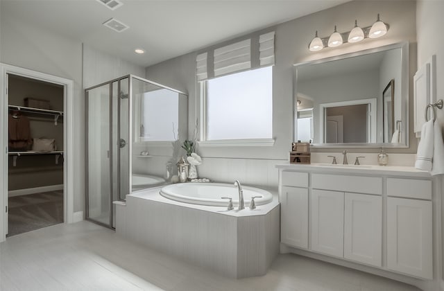 bathroom with vanity and shower with separate bathtub