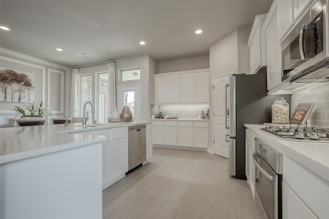 kitchen featuring tasteful backsplash, light hardwood / wood-style flooring, white cabinets, and stainless steel appliances