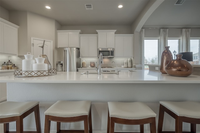 kitchen with white cabinets, sink, appliances with stainless steel finishes, and a breakfast bar area