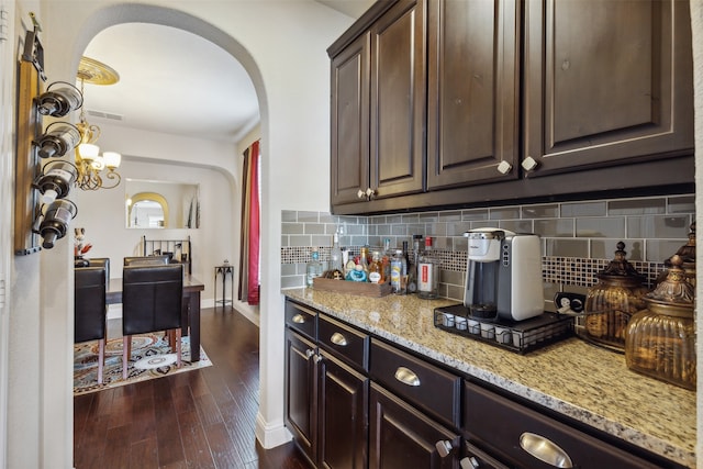 kitchen featuring light stone countertops, dark hardwood / wood-style floors, tasteful backsplash, and dark brown cabinets