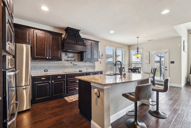 kitchen featuring plenty of natural light, custom range hood, dark hardwood / wood-style flooring, and a kitchen island with sink