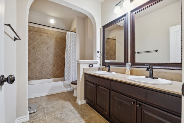 full bathroom with double sink vanity, toilet, tile floors, and shower / tub combo